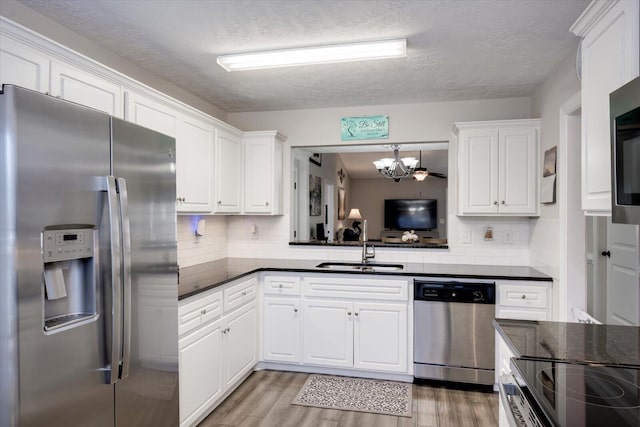 kitchen featuring sink, light wood-type flooring, stainless steel appliances, decorative backsplash, and white cabinets