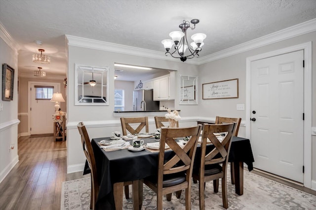 dining space featuring hardwood / wood-style floors, ceiling fan with notable chandelier, ornamental molding, and a textured ceiling