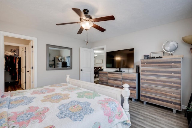 bedroom featuring ceiling fan, wood-type flooring, and a spacious closet