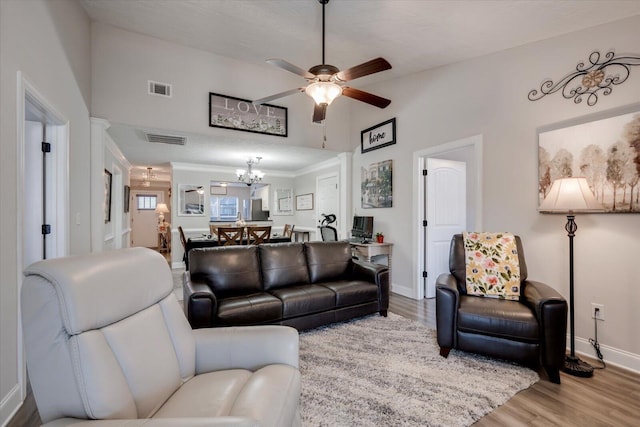 living room with vaulted ceiling, ceiling fan with notable chandelier, and light wood-type flooring