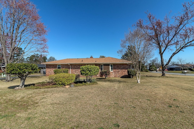 view of front of home featuring brick siding, a chimney, and a front yard