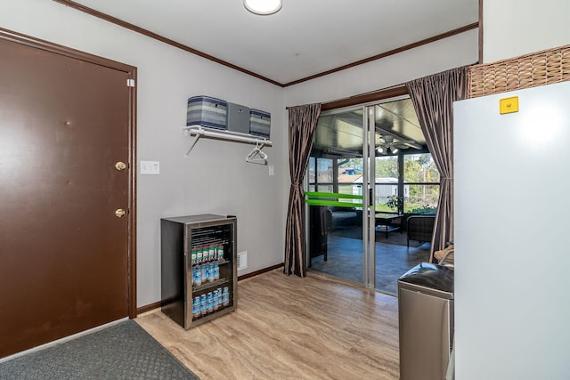 corridor with baseboards, beverage cooler, ornamental molding, and light wood finished floors