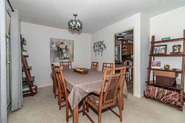 dining room featuring an inviting chandelier, light colored carpet, and baseboards