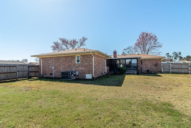 rear view of property with cooling unit, a chimney, brick siding, and a yard