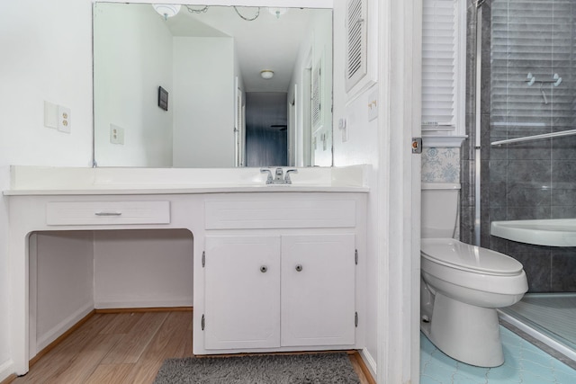 bathroom featuring a shower, toilet, wood finished floors, and vanity