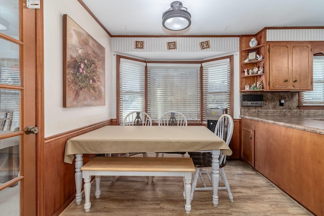 dining space featuring light wood finished floors, wainscoting, and ornamental molding