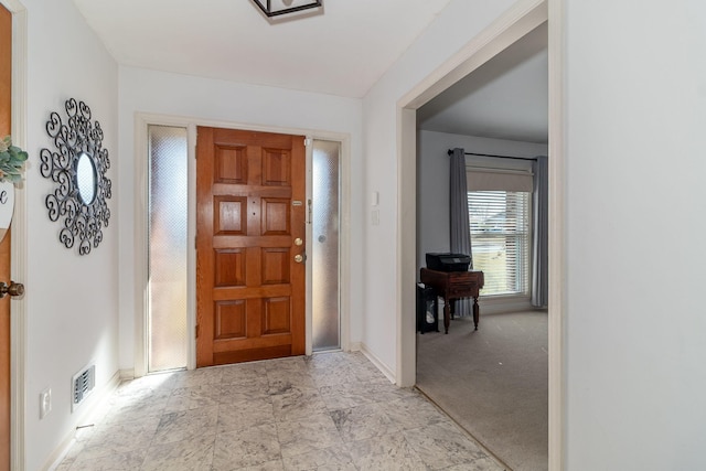 entrance foyer featuring baseboards, visible vents, and light carpet