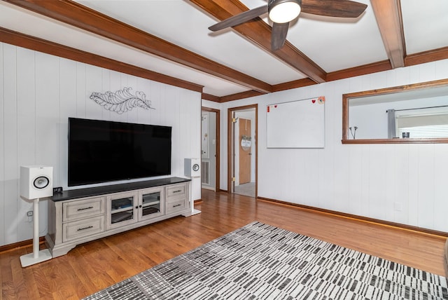 unfurnished living room featuring light wood-type flooring, baseboards, beamed ceiling, and a ceiling fan