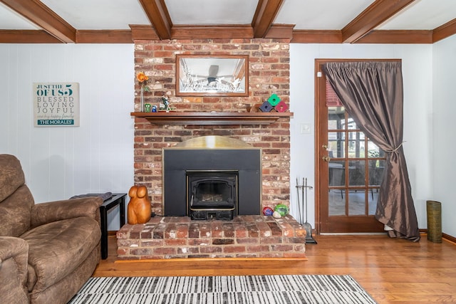 living area with a brick fireplace, beamed ceiling, and wood finished floors