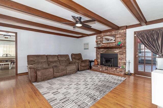 living area featuring baseboards, ceiling fan, beamed ceiling, light wood-style flooring, and a fireplace