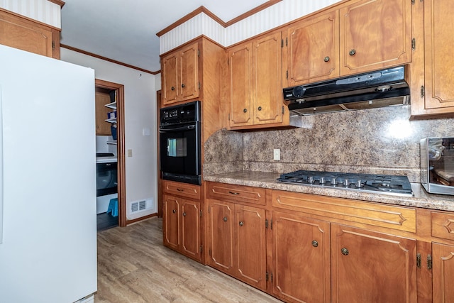 kitchen featuring visible vents, oven, under cabinet range hood, stainless steel gas cooktop, and ornamental molding