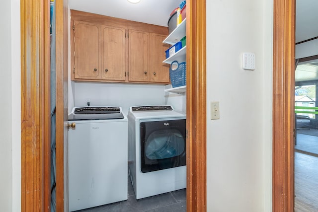 washroom featuring cabinet space, independent washer and dryer, and dark tile patterned floors