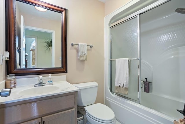 bathroom featuring enclosed tub / shower combo, vanity, and toilet