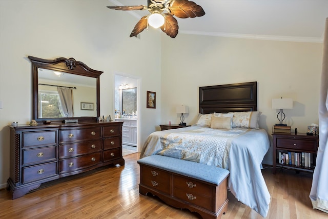 bedroom featuring a ceiling fan, ensuite bath, ornamental molding, and wood finished floors