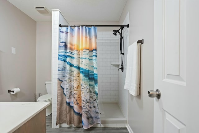 full bath featuring toilet, a stall shower, wood finished floors, and vanity