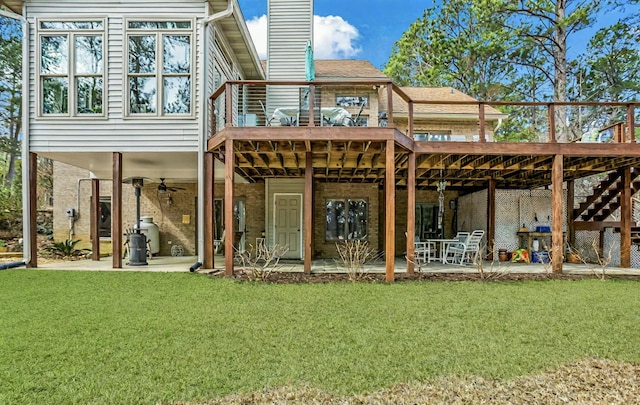 rear view of property featuring a patio, a chimney, stairs, a deck, and a yard