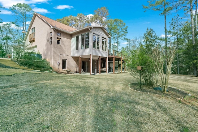 rear view of house featuring a lawn and a deck