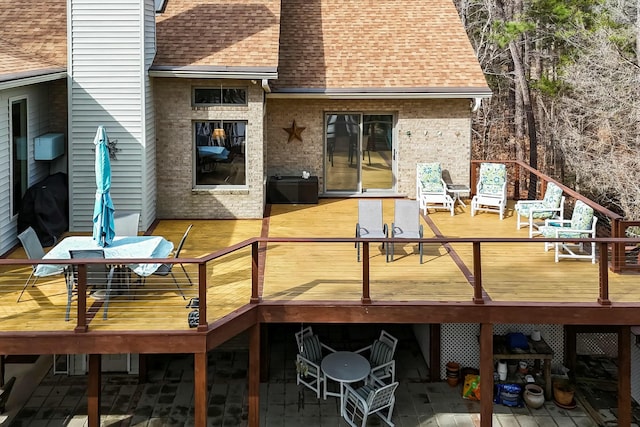 back of house with brick siding and roof with shingles