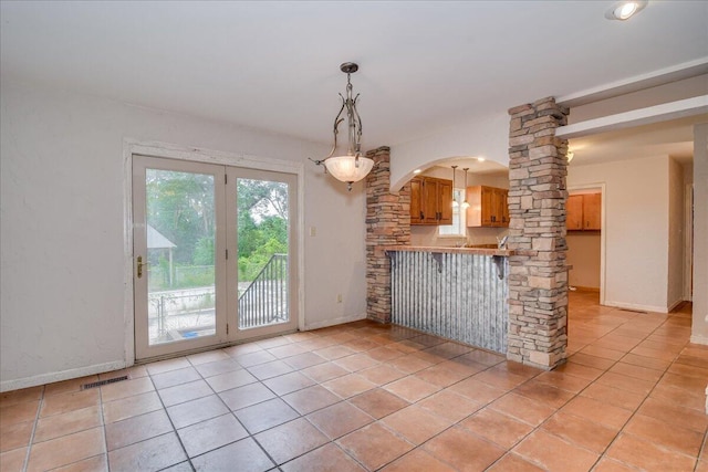 kitchen featuring kitchen peninsula, ornate columns, and light tile patterned flooring