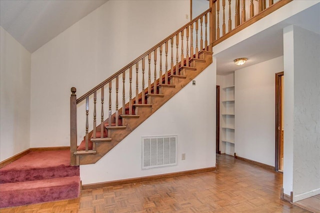 stairs featuring parquet floors and high vaulted ceiling