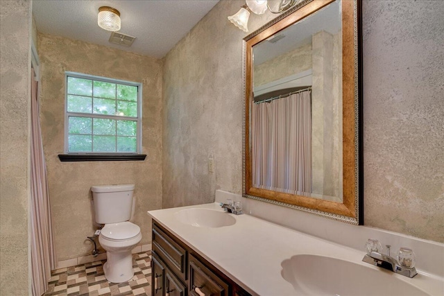 bathroom with vanity, a textured ceiling, and toilet