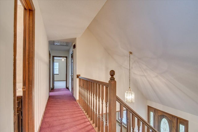 corridor featuring a chandelier, carpet floors, and lofted ceiling