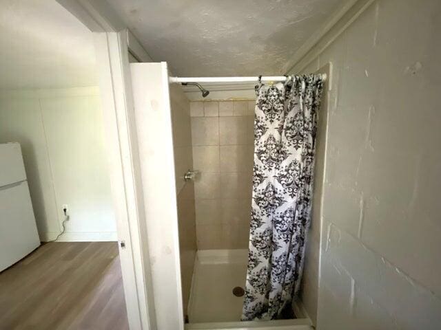 bathroom with hardwood / wood-style flooring and walk in shower