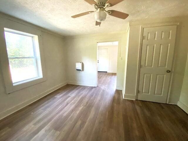 unfurnished room with dark wood-type flooring, ceiling fan, and a textured ceiling