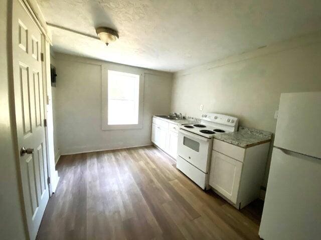 kitchen with hardwood / wood-style flooring, white appliances, sink, and white cabinets