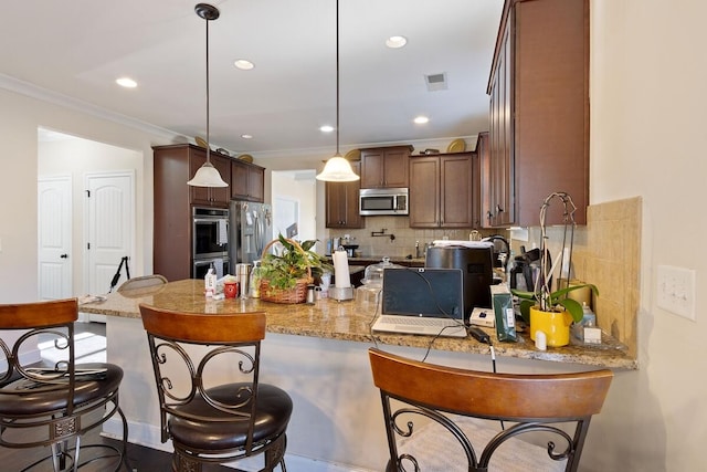 kitchen with hanging light fixtures, decorative backsplash, stainless steel appliances, and kitchen peninsula