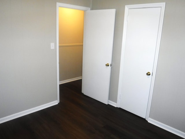 unfurnished bedroom with a closet and dark wood-type flooring