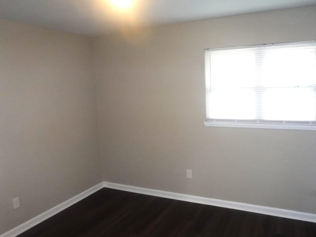 unfurnished room with dark hardwood / wood-style flooring and plenty of natural light