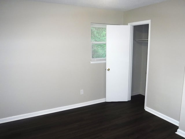 unfurnished bedroom featuring dark hardwood / wood-style flooring and a closet