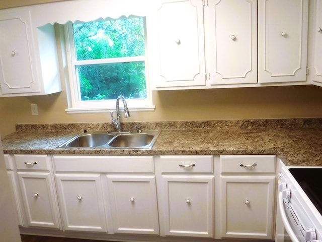 kitchen featuring white cabinetry, sink, and range