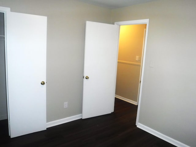 unfurnished bedroom with dark hardwood / wood-style floors and a closet