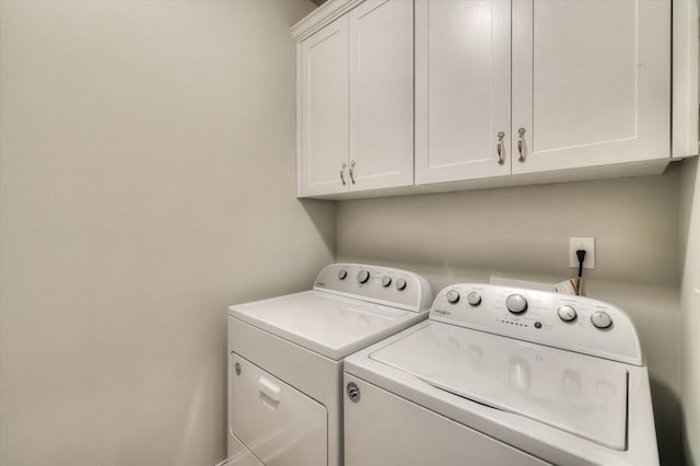 clothes washing area with washing machine and clothes dryer and cabinets