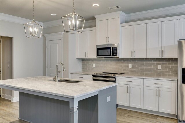 kitchen featuring sink, white cabinetry, stainless steel appliances, and an island with sink