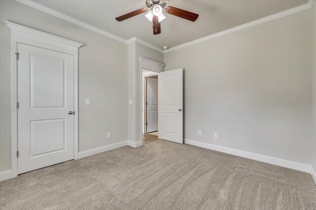 unfurnished bedroom featuring ceiling fan, light colored carpet, and crown molding