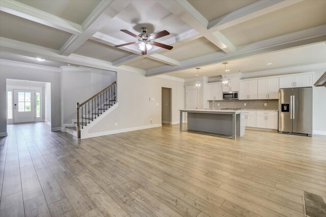 kitchen with a kitchen island with sink, hanging light fixtures, coffered ceiling, and appliances with stainless steel finishes