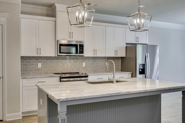 kitchen featuring a kitchen island with sink, stainless steel appliances, and decorative light fixtures