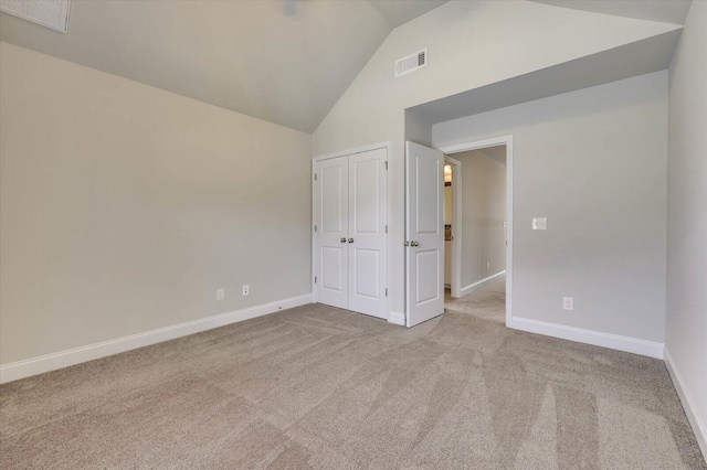 unfurnished bedroom featuring light carpet, a closet, and lofted ceiling