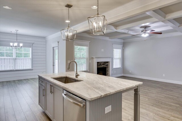 kitchen featuring ceiling fan, sink, coffered ceiling, stainless steel dishwasher, and an island with sink