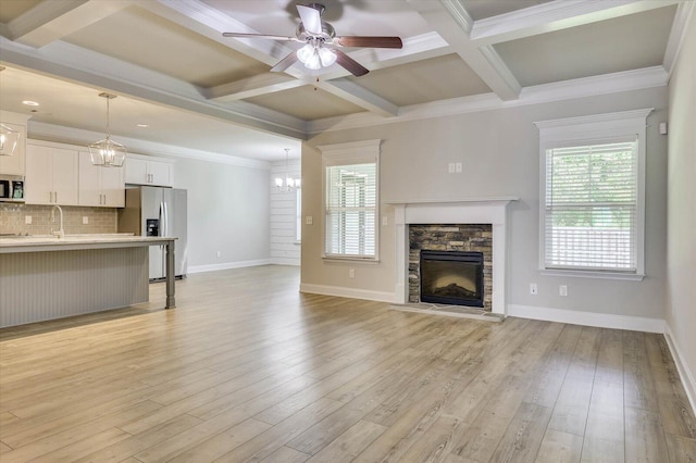 unfurnished living room with a fireplace, light wood-type flooring, ceiling fan, and coffered ceiling