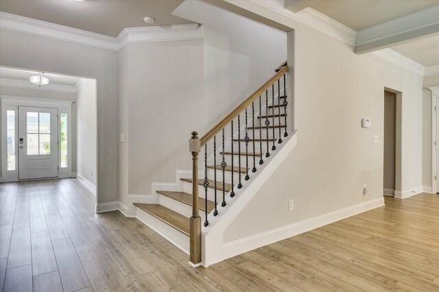 entryway with light wood-type flooring and crown molding