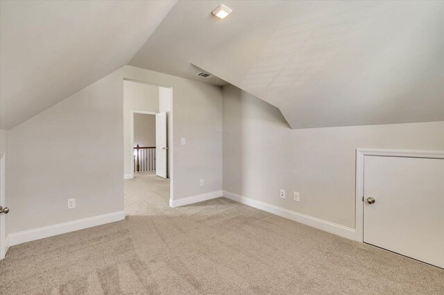 bonus room with light colored carpet and lofted ceiling