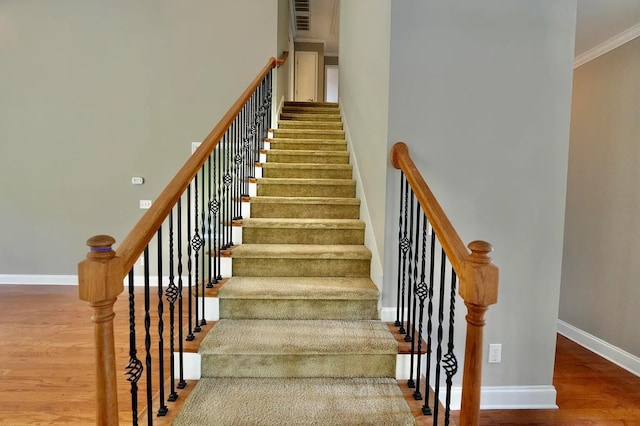 staircase with hardwood / wood-style flooring, ornamental molding, and a high ceiling