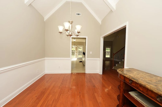 dining area featuring high vaulted ceiling, beam ceiling, hardwood / wood-style floors, and a notable chandelier