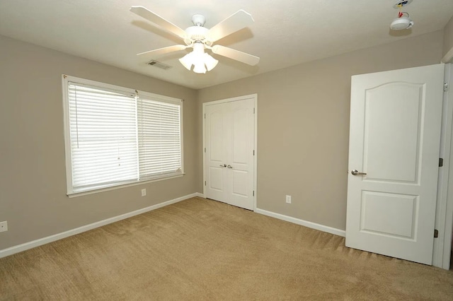 unfurnished bedroom featuring ceiling fan, light colored carpet, and a closet