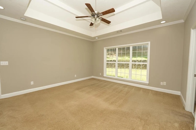 carpeted spare room with crown molding, a tray ceiling, and ceiling fan