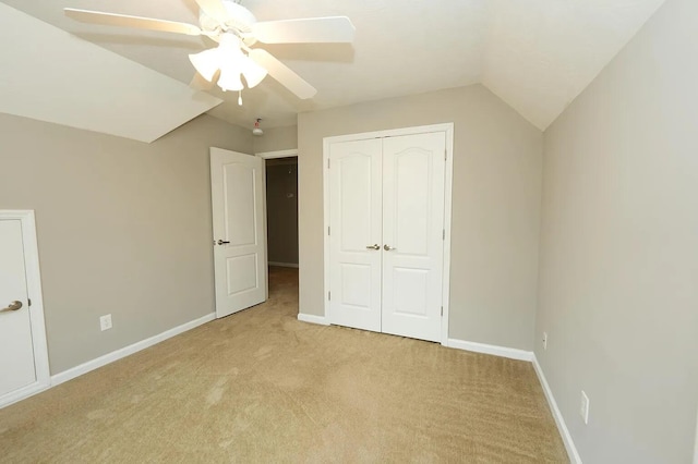 unfurnished bedroom featuring lofted ceiling, light colored carpet, ceiling fan, and a closet